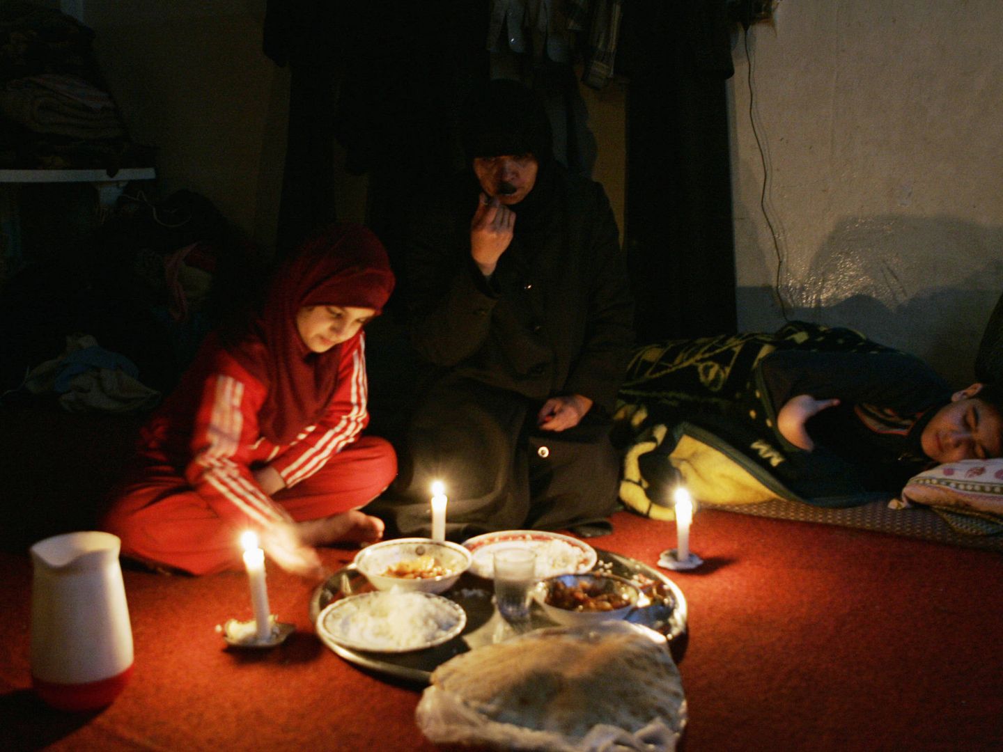 Una migrante iraquí y sus hijos comen durante un apagón en Damasco, Siria. (Reuters)