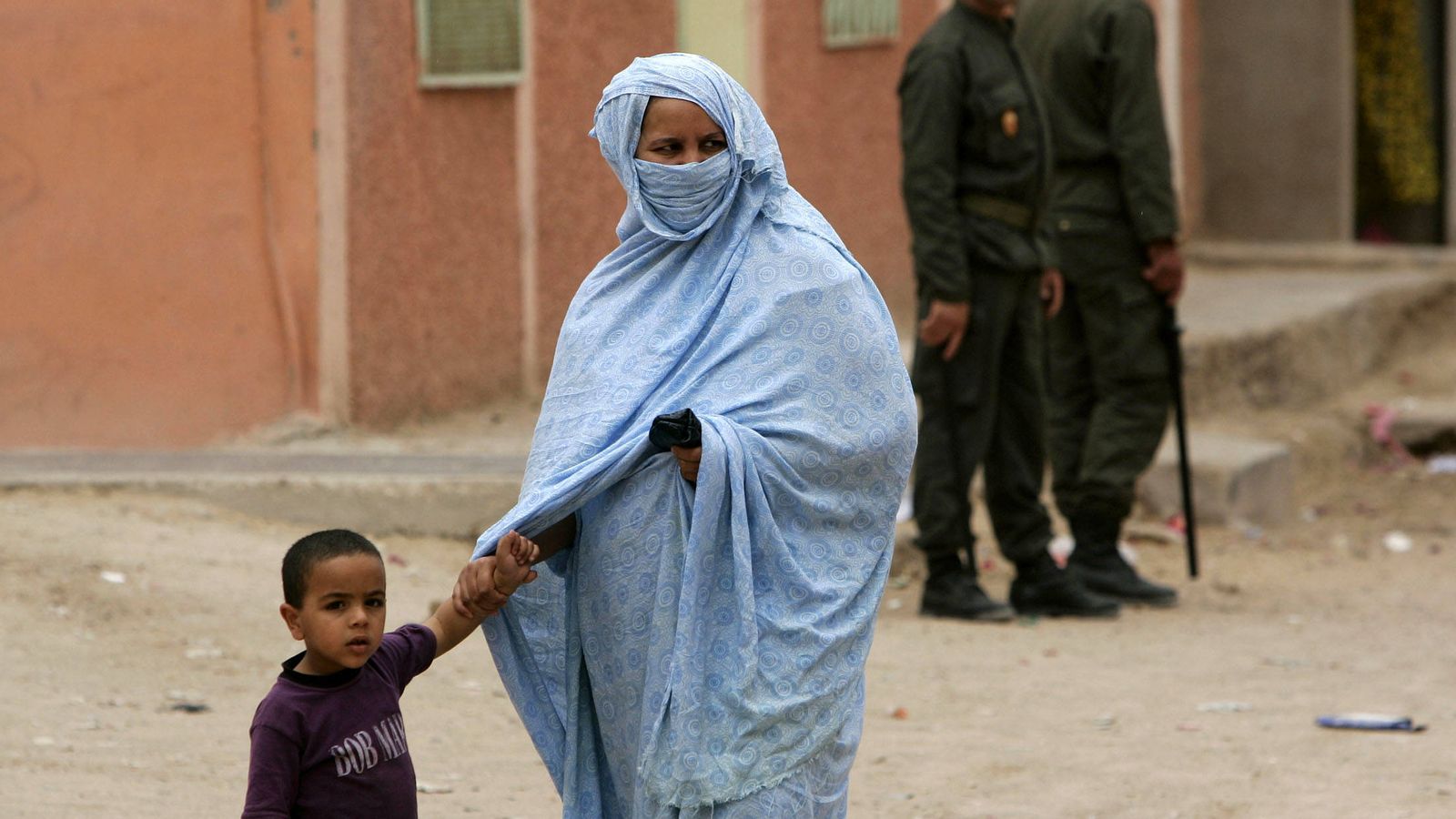 Foto: Una madre saharaui y su hijo pasan delante de dos policías marroquíes en El Aaiun, en 2005 (Reuters)