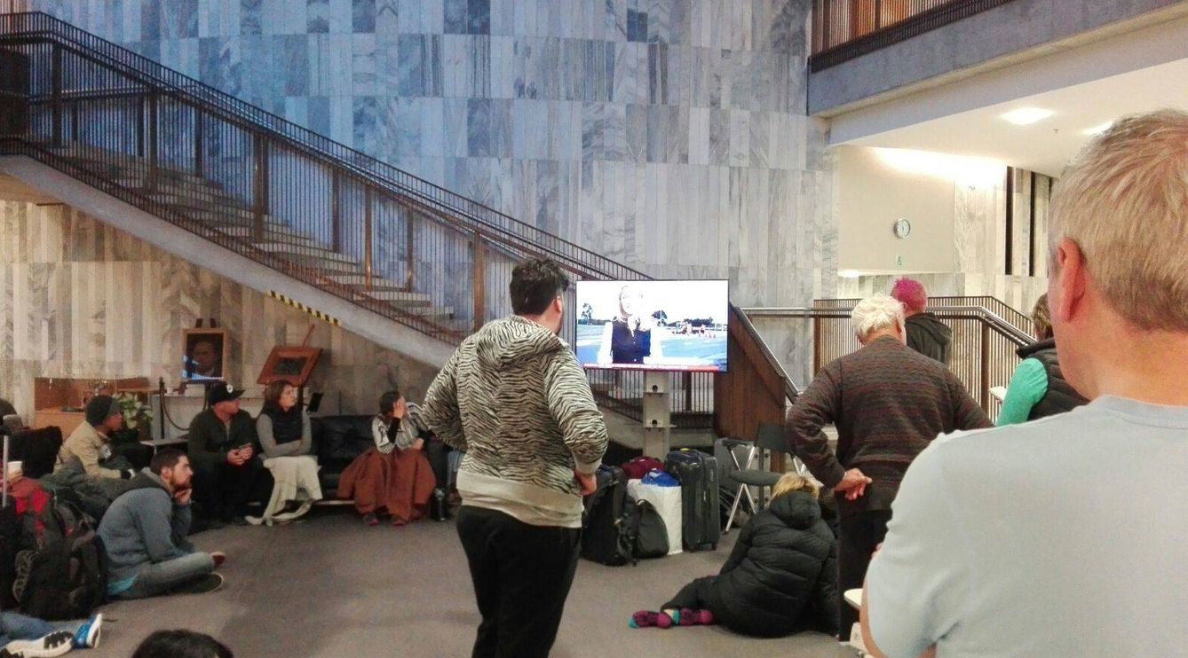 Evacuados ven las noticias en el lobby del Parlamento de Nueva Zelanda