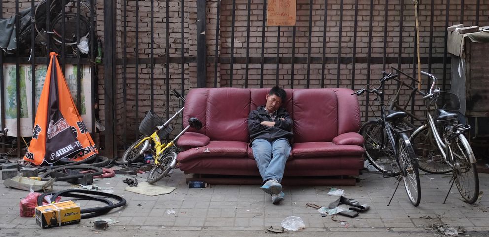 Un hombre duerme en su negocio de reparación de bicicletas en Pekín (Reuters).