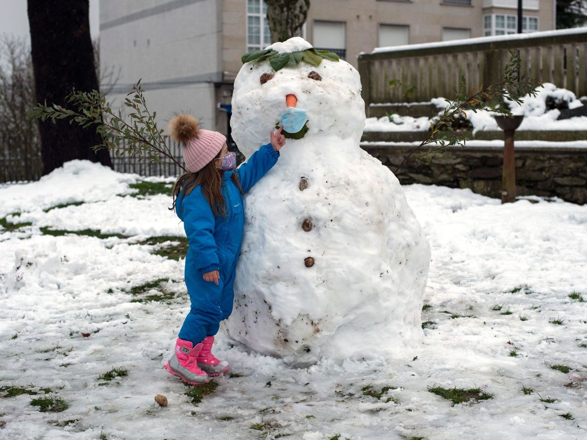 Foto: Una niña con un muñeco de nieve con mascarilla en Cantabria. (EFE)