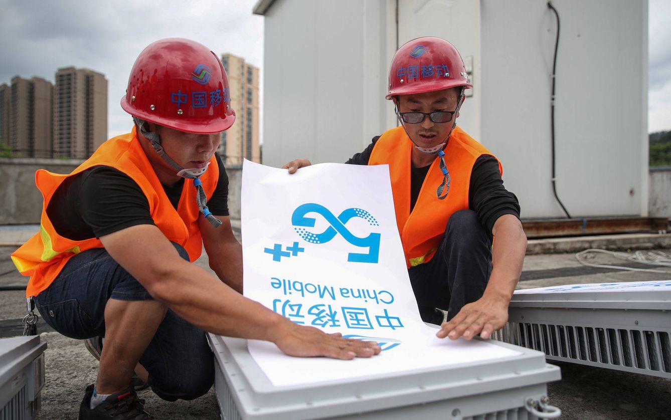 Trabajadores colocan un letrero de China Mobile 5G en un equipo de la ciudad china de Fenggang. (Reuters)