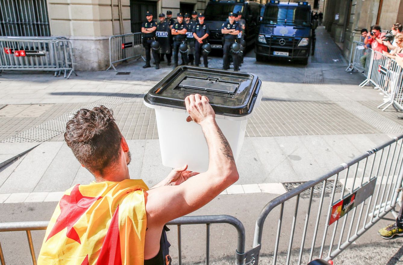 Un joven muestra una urna empleada el 1-O a los policías apostados en la Via Laietana, en Barcelona. (EFE)