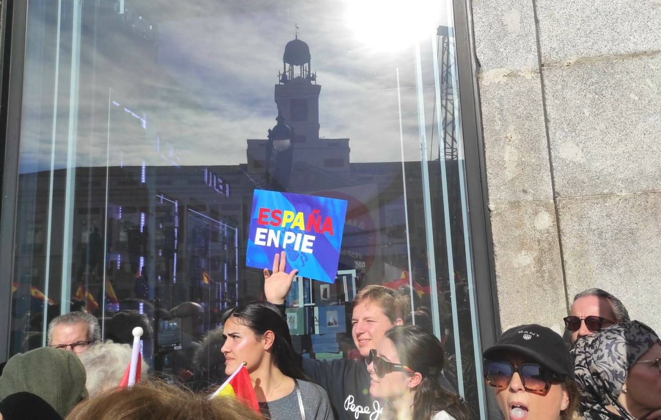 Un manifestante muestra un cartel con el lema 'España en pie', el la Puerta del Sol de Madrid. (L.B.)