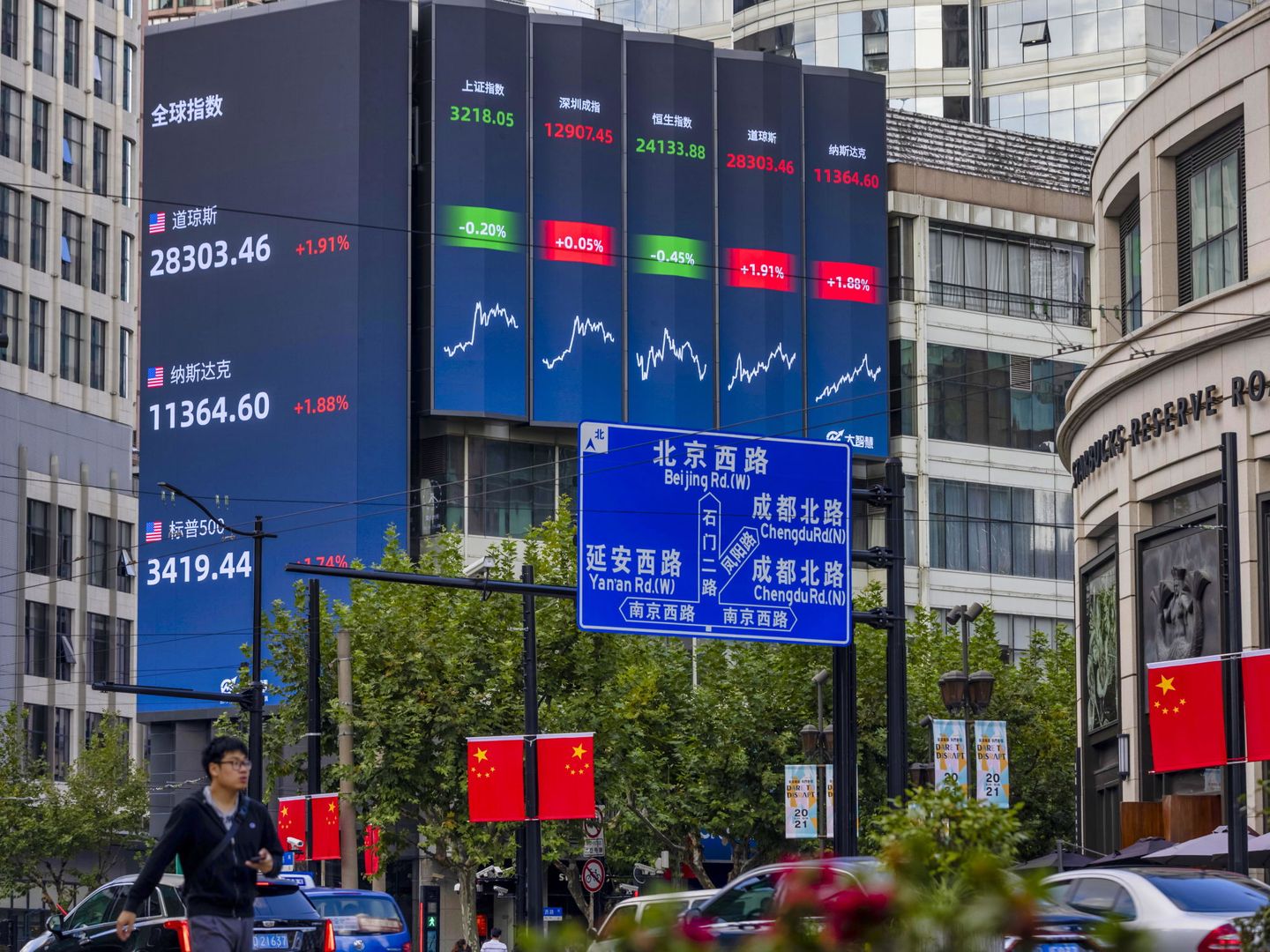 Ciudadanos pasean frente a una pantalla que muestra los índices de bolsa mundiales en Shanghái. (EFE)