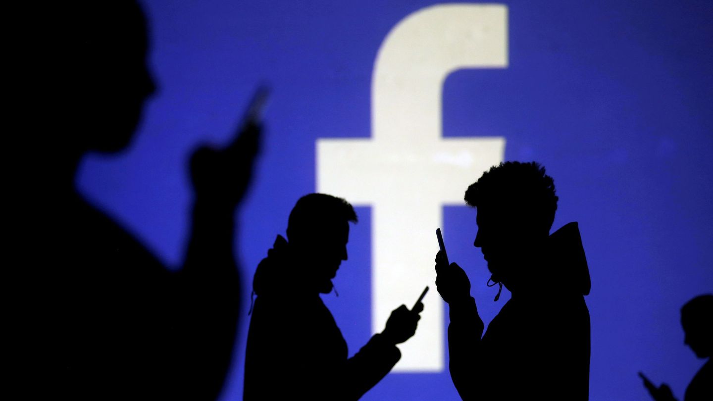 FILE PHOTO: Silhouettes of mobile users are seen next to a screen projection of Facebook logo in this picture illustration taken March 28, 2018.  REUTERS Dado Ruvic Illustration File Photo