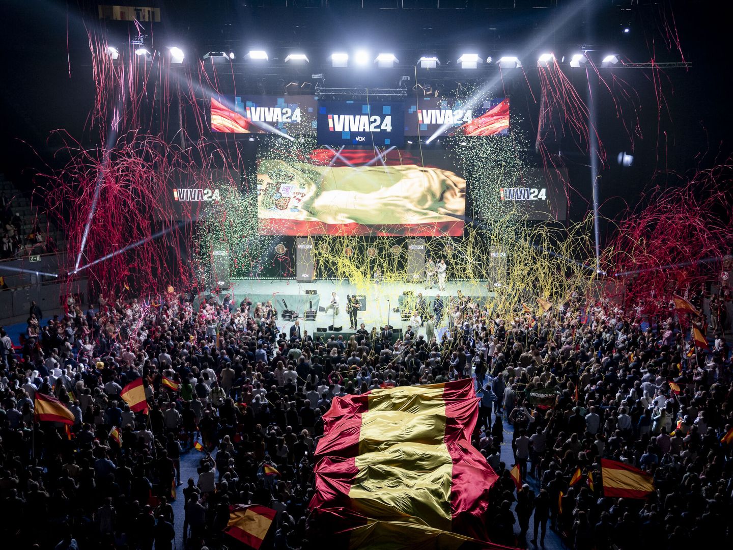 Los asistentes sujetan una bandera española tras el acto 'Viva 24' de Vox, en el Palacio de Vistalegre. (Europa Press/Pérez Meca)
