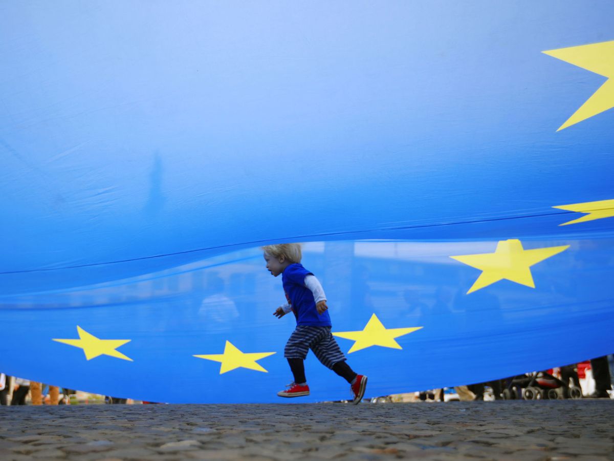 Foto: Un joven corre bajo una gran bandera europea. (Reuters)