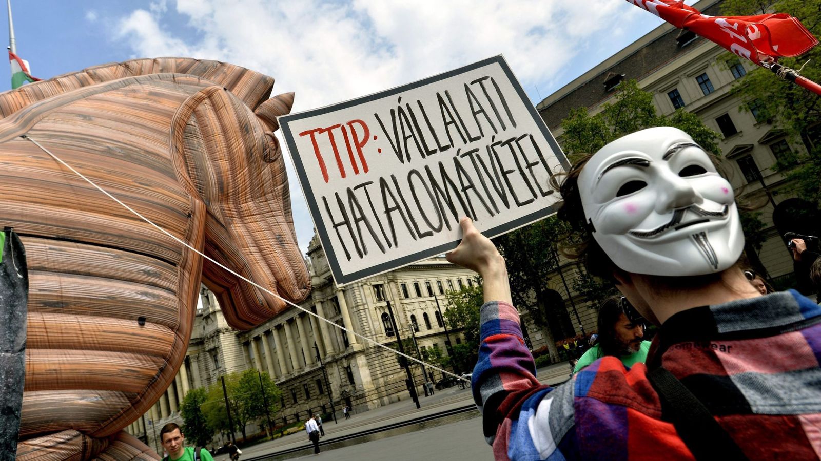 Foto: Un activista muestra un cartel que reza 'TTIP: golpe de Estado corporativo' durante una protesta. (EFE)