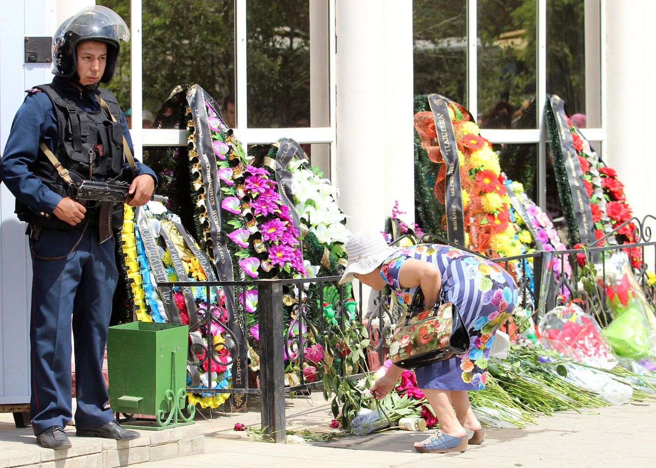 Una mujer deposita flores junto a una armería atacada por extremistas en Aktobe, Kazajistán, en junio de 2016 (Reuters)