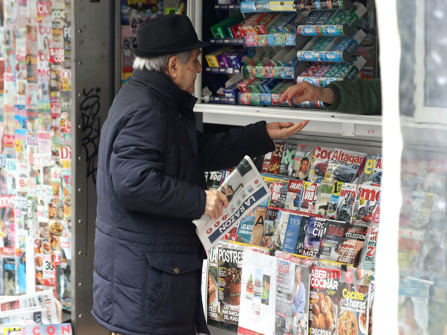 Una persona compra un periódico en un quiosco español. (EFE)