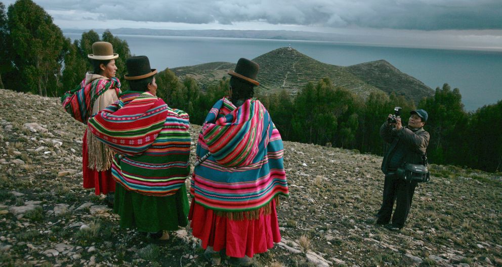 Un hombre saca una fotografía de un grupo de indígenes bolivianos en Khona Bahía. (Reuters)