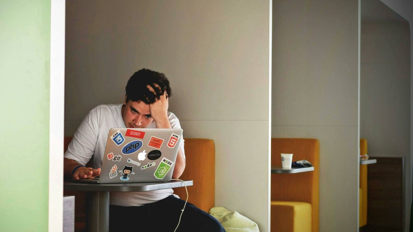Foto: Un joven estresado mira su portátil en un café. (Pexels)
