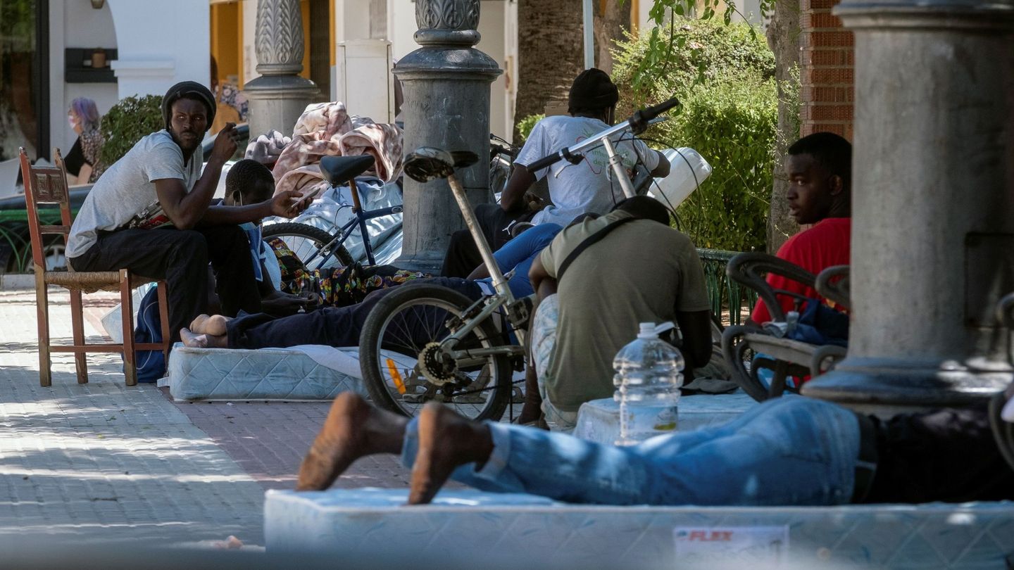Un grupo de inmigrantes descansa en una calle de Lepe tras haber ardido su campamento. (EFE/Julián Pérez)