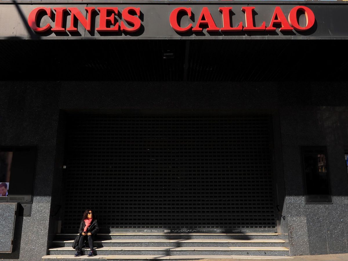Foto: Una mujer descansa junto a los cines Callao en Madrid. (EFE)