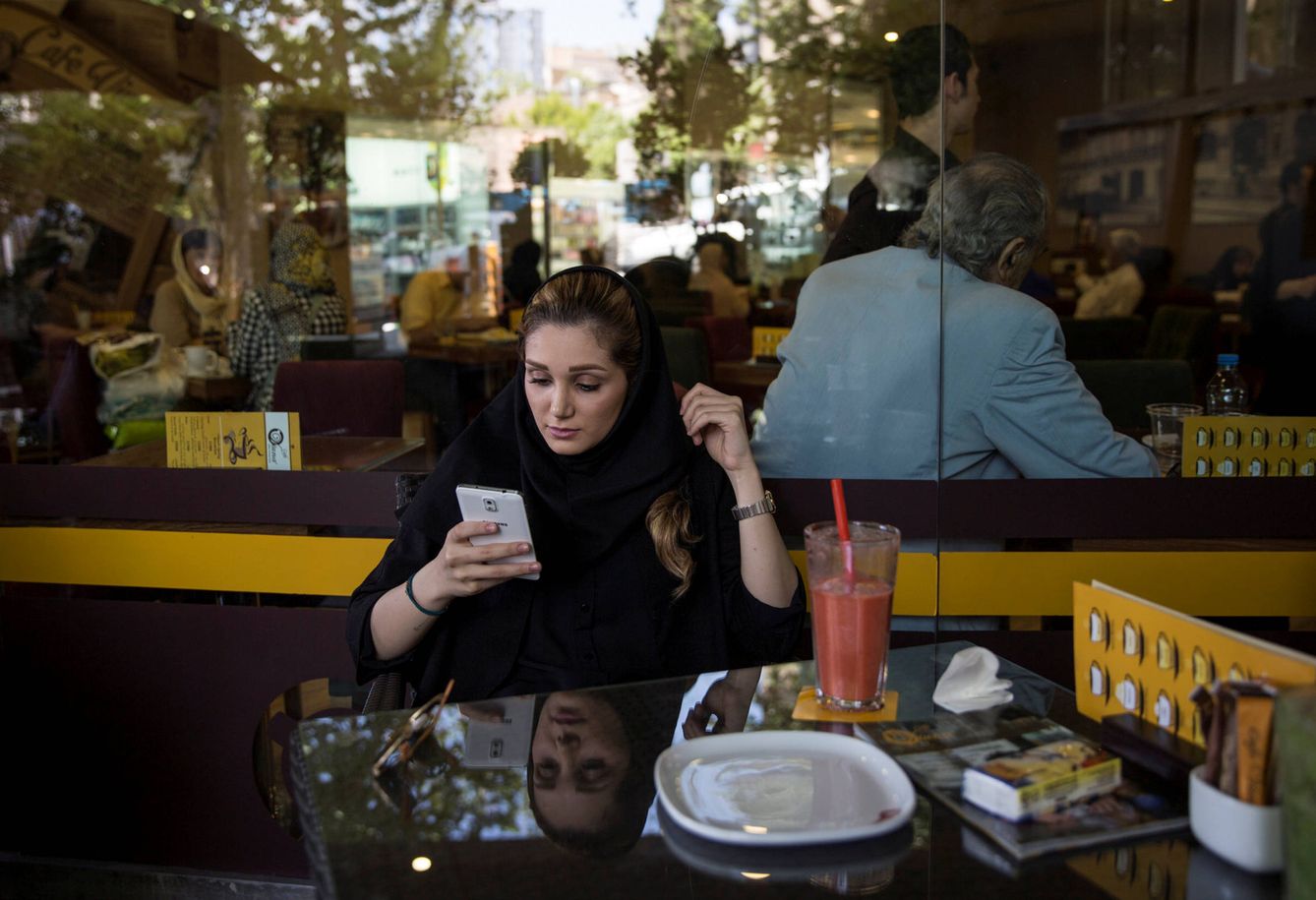 Una mujer iraní sigue las noticias en su teléfono móvil en un café de Teherán. (Reuters)