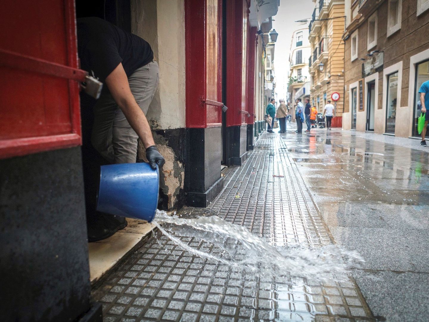 Una persona saca agua de su casa inundada en Cádiz. (EFE/Román Ríos)