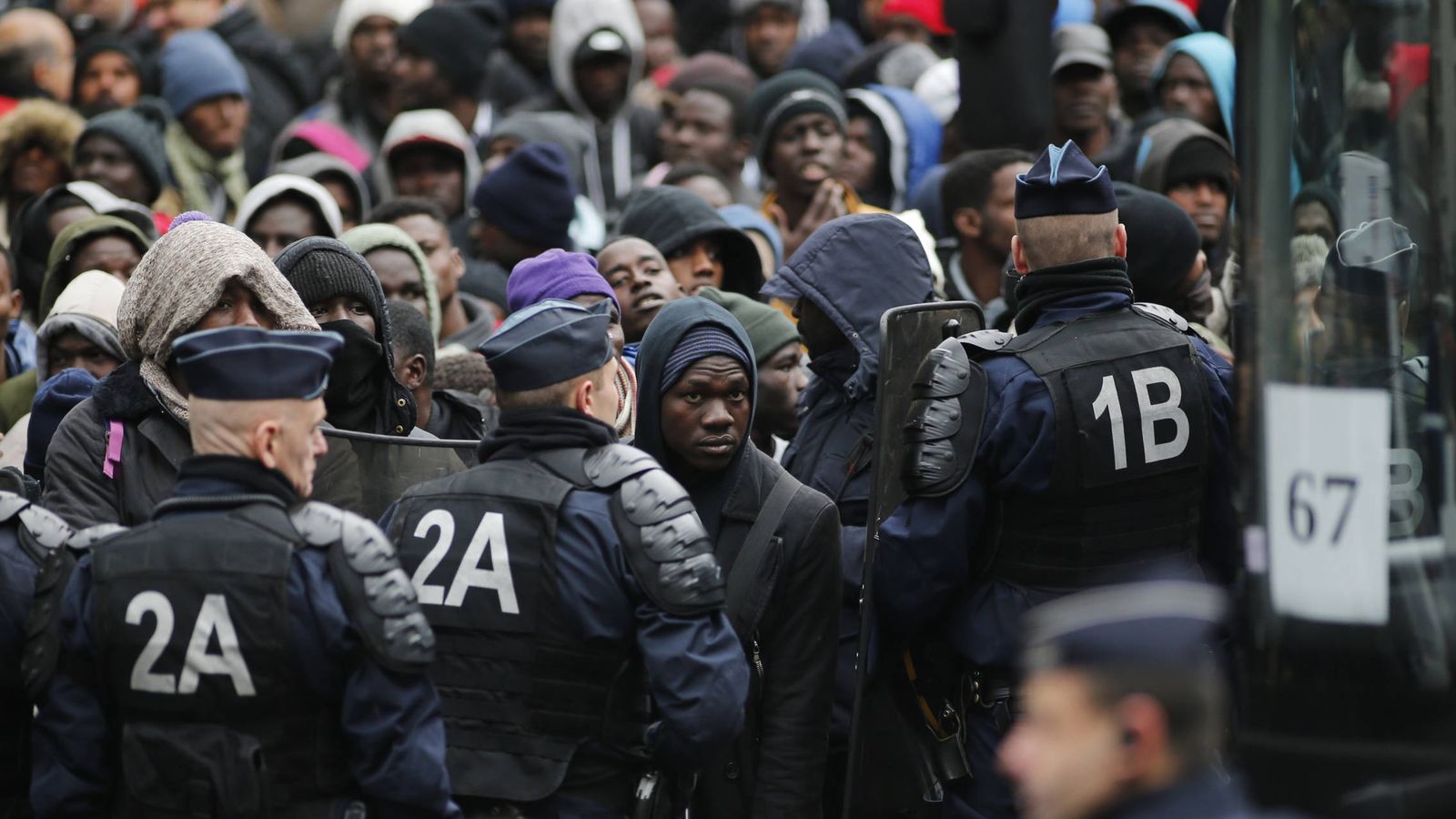 Foto: Agentes de policía franceses ante migrantes transferidos por las autoridades a centros de detención, en París (Reuters). 