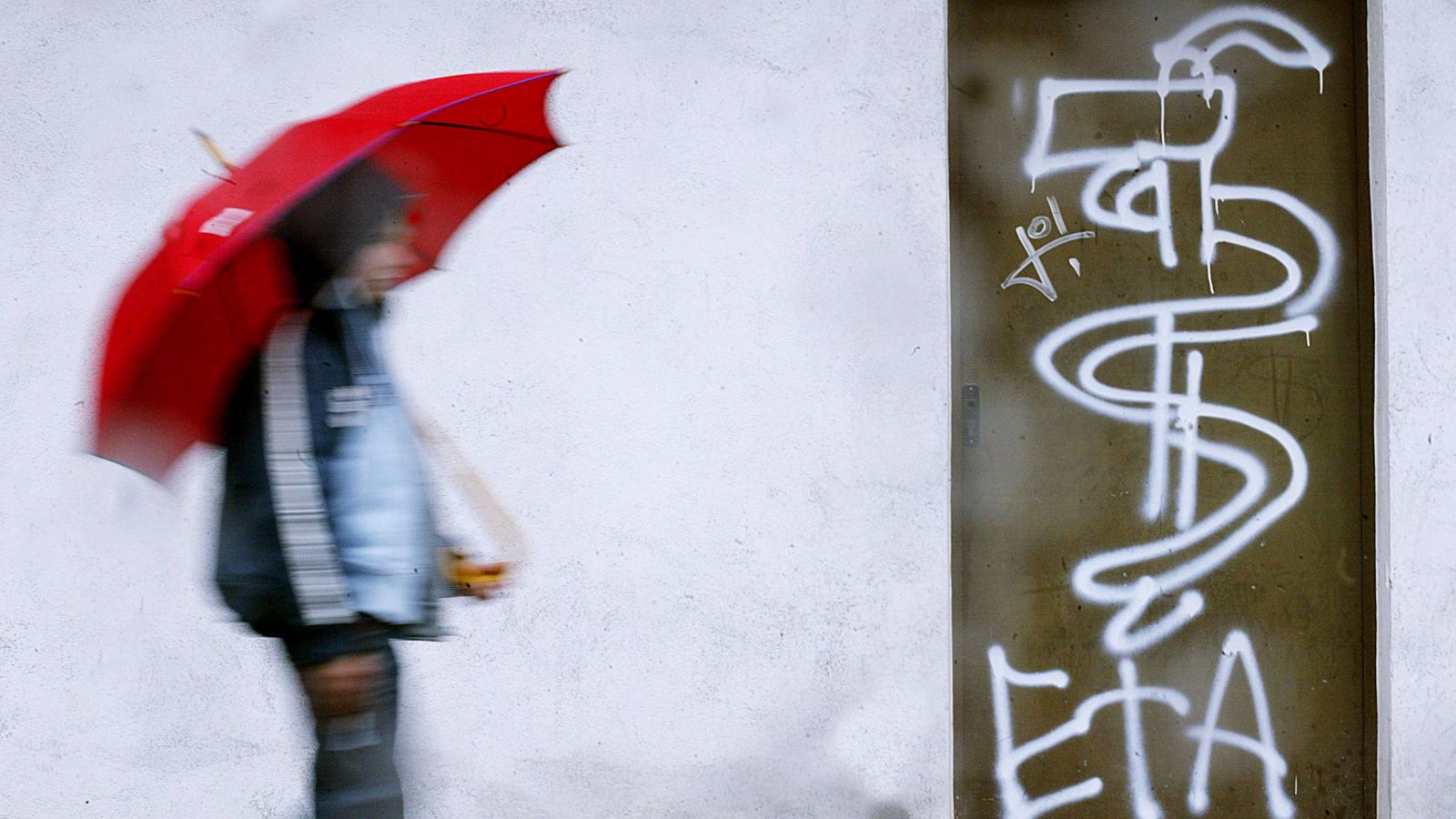 Foto: Un joven pasa junto a una pintada de ETA en la ciudad de Guernica. (Reuters)