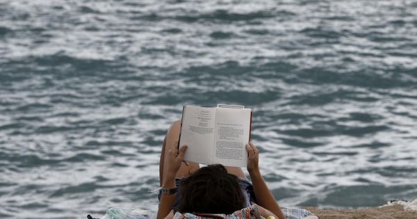 Foto: Una mujer leyendo en la Barceloneta (Efe)