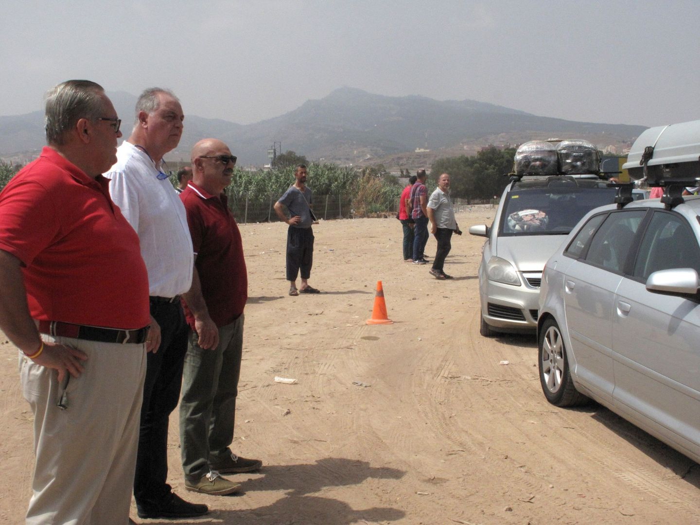 El presidente de Vox Melilla, Jesús Delgado Aboy (segundo por la izquierda), observa los vehículos que aguardan ante la frontera de Melilla con Marruecos. (EFE)