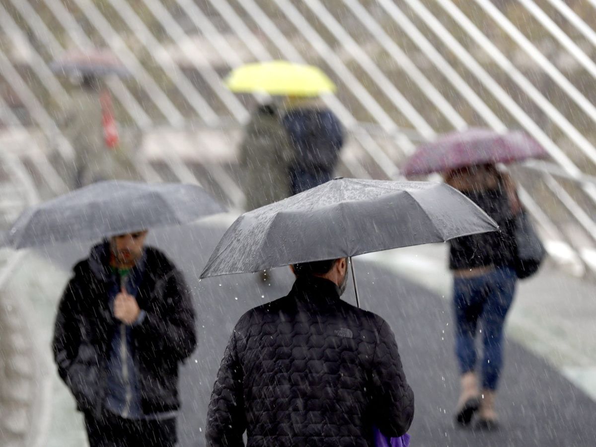 Foto: Varias personas se protegen de la lluvia en Bilbao. (EFE)