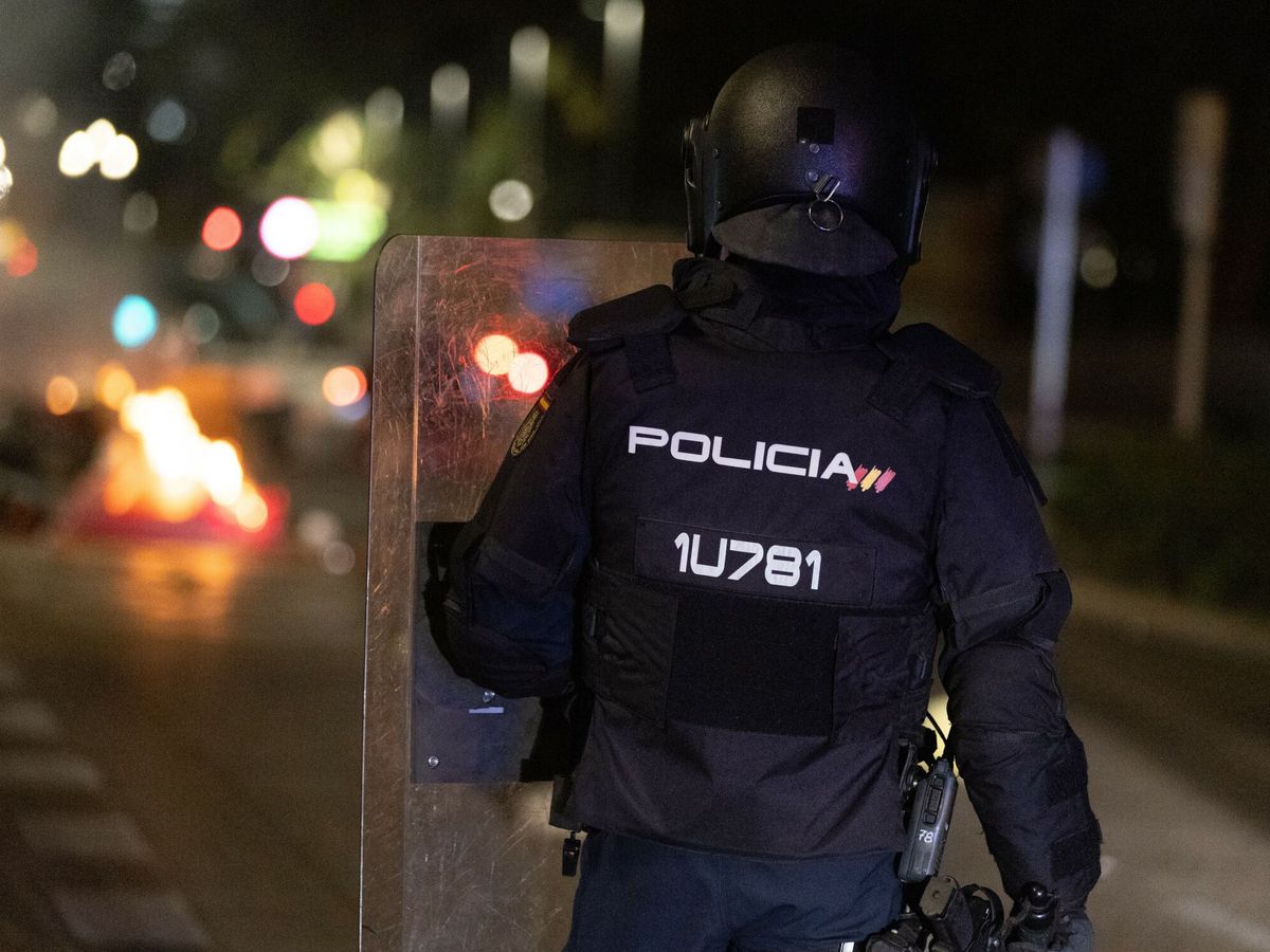 Foto: Un policía sujeta un escudo observando la barricada de los manifestantes concentrados en la sede del PSOE en la calle Ferraz. (Europa Press/Eduardo Parra)
