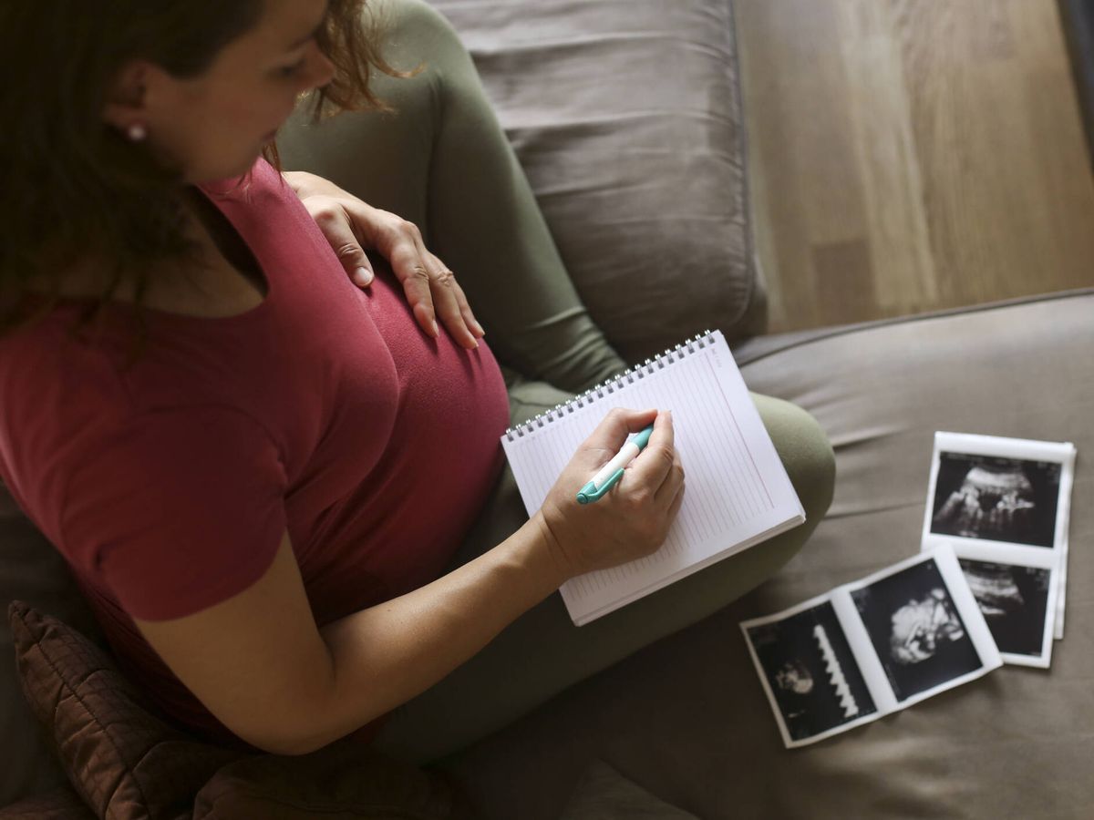Foto: Una mujer embarazada apunta posibles nombres para su bebé. (iStock)