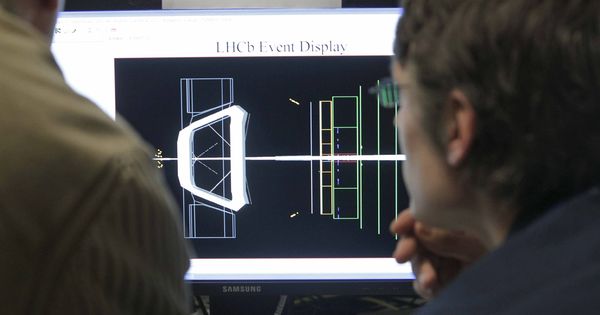 Foto: Un par de científicos observan una de las pantallas en la sala de control de experiencias del LHCb (EFE)