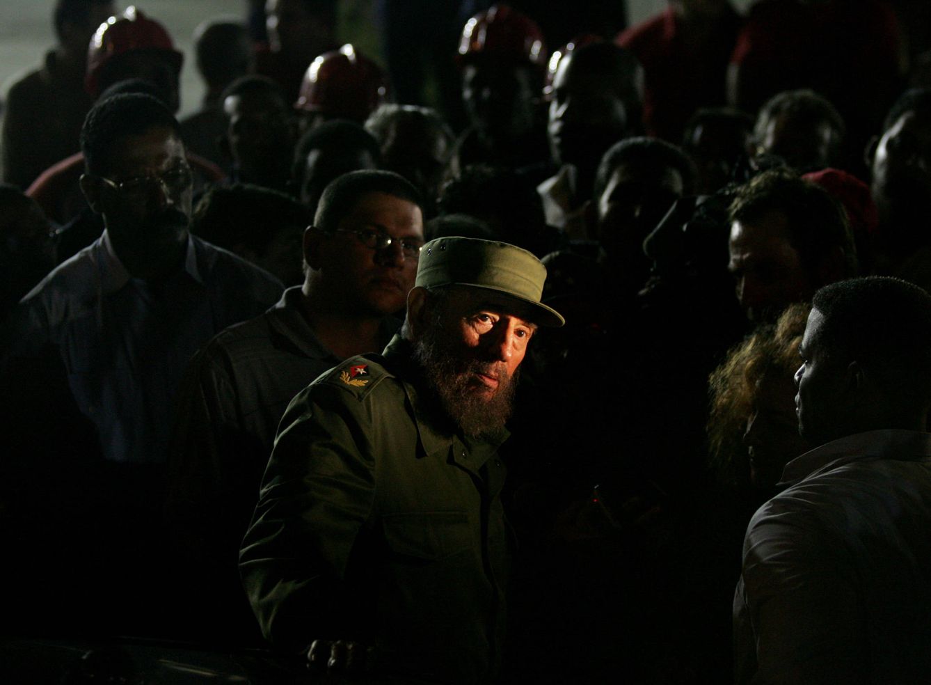 Las luces de neón iluminan el rostro de Fidel Castro durante una visita nocturna a una obra, en enero de 2006. (Reuters)
