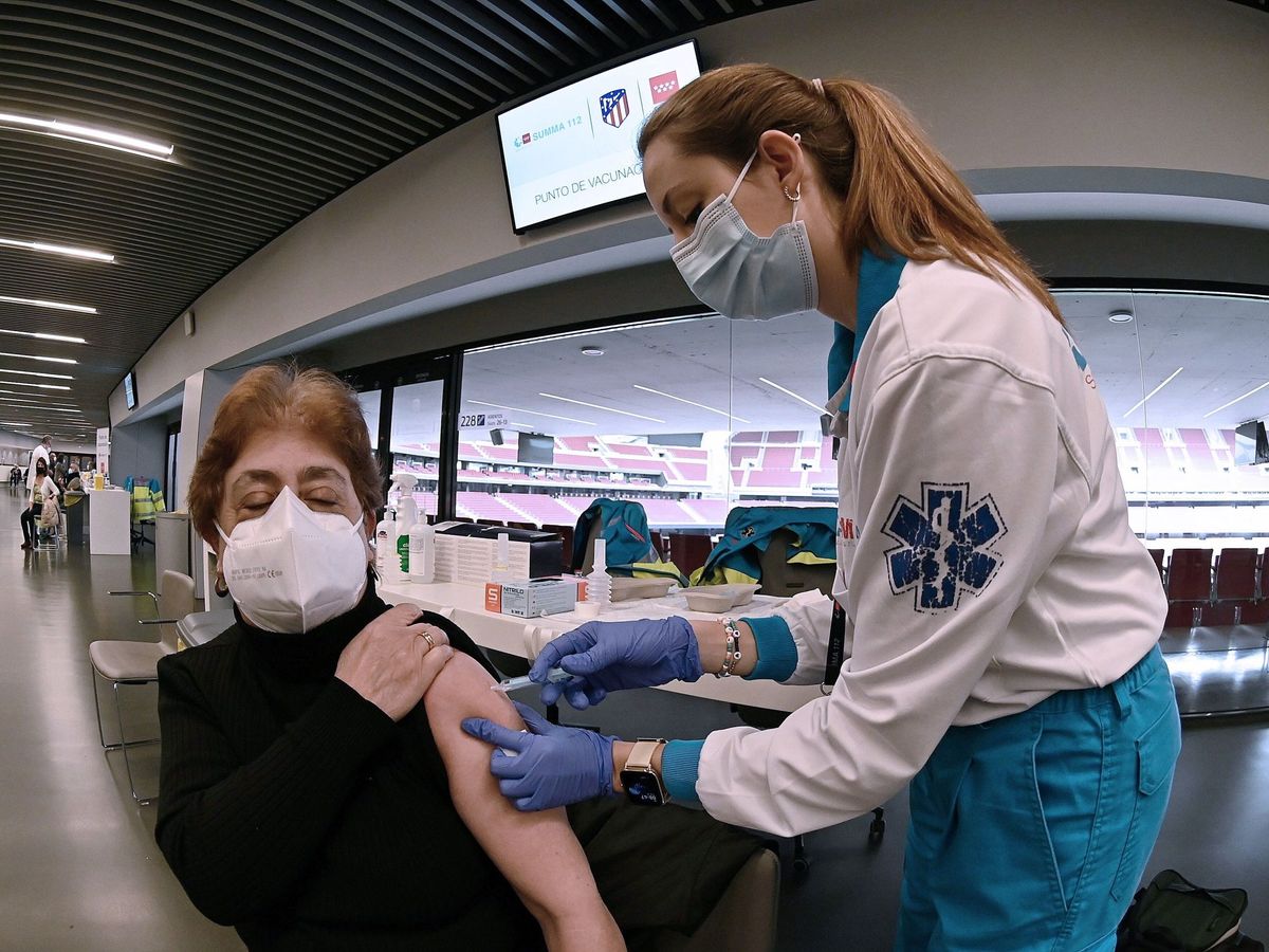 Foto: Una sanitaria vacuna a una mujer en el Wanda Metropolitano en Madrid. (EFE)