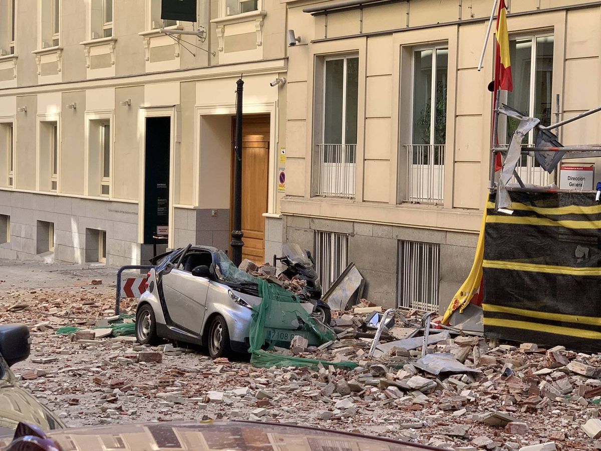 Foto: Un vehículo estacionado frente al inmueble ha resultado dañado por la caída de la cornisa. (Emergencias Madrid)