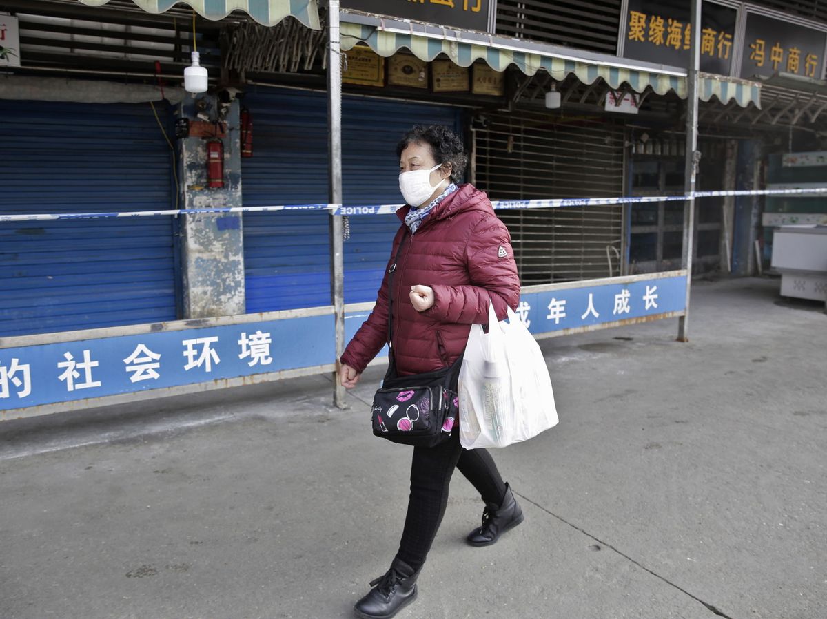 Foto: Una mujer pasea junto al mercado de Huanan Seafood Wholesale Market. (EFE)