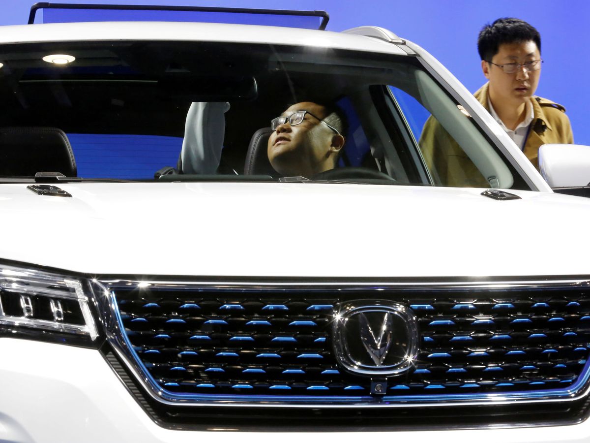 Foto: Un visitante, en el interior de un coche eléctrico, en un salón del automóvil en China. (Reuters)