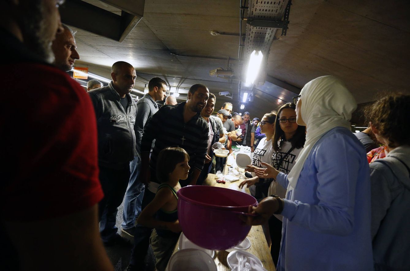Migrantes y refugiados reciben la comida que les ofrecen unos voluntarios en Salzburgo, Austria (Reuters). 