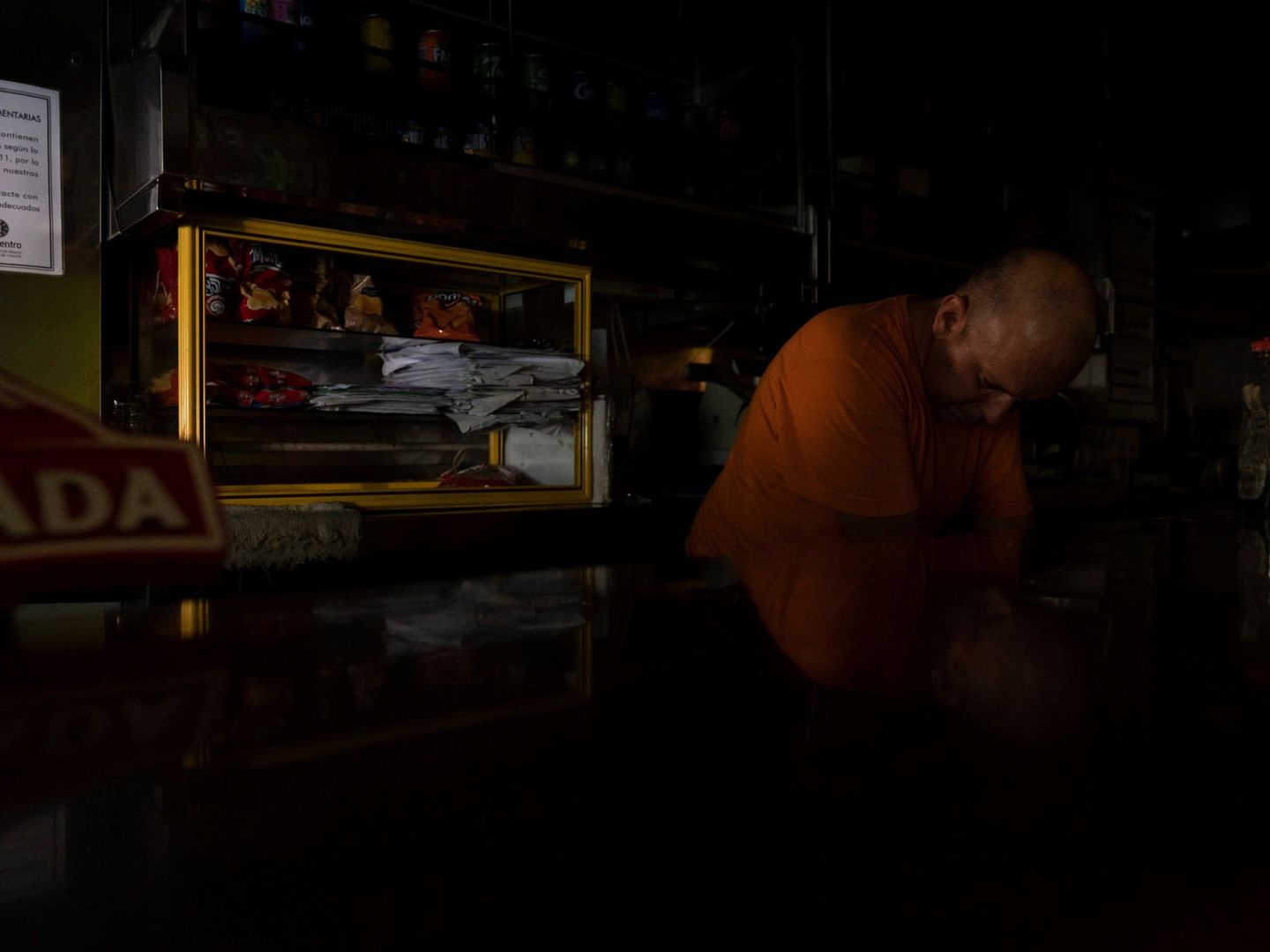 Un empleado de una cafetería de Santa Cruz de Tenerife intenta trabajar a oscuras mientras espera a que se restablezca el suministro eléctrico. (EFE)