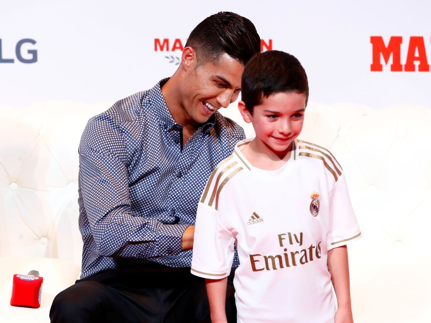 Cristiano Ronaldo le firma la camseta del Madrid a uno de los niños presentes en el acto. (EFE)