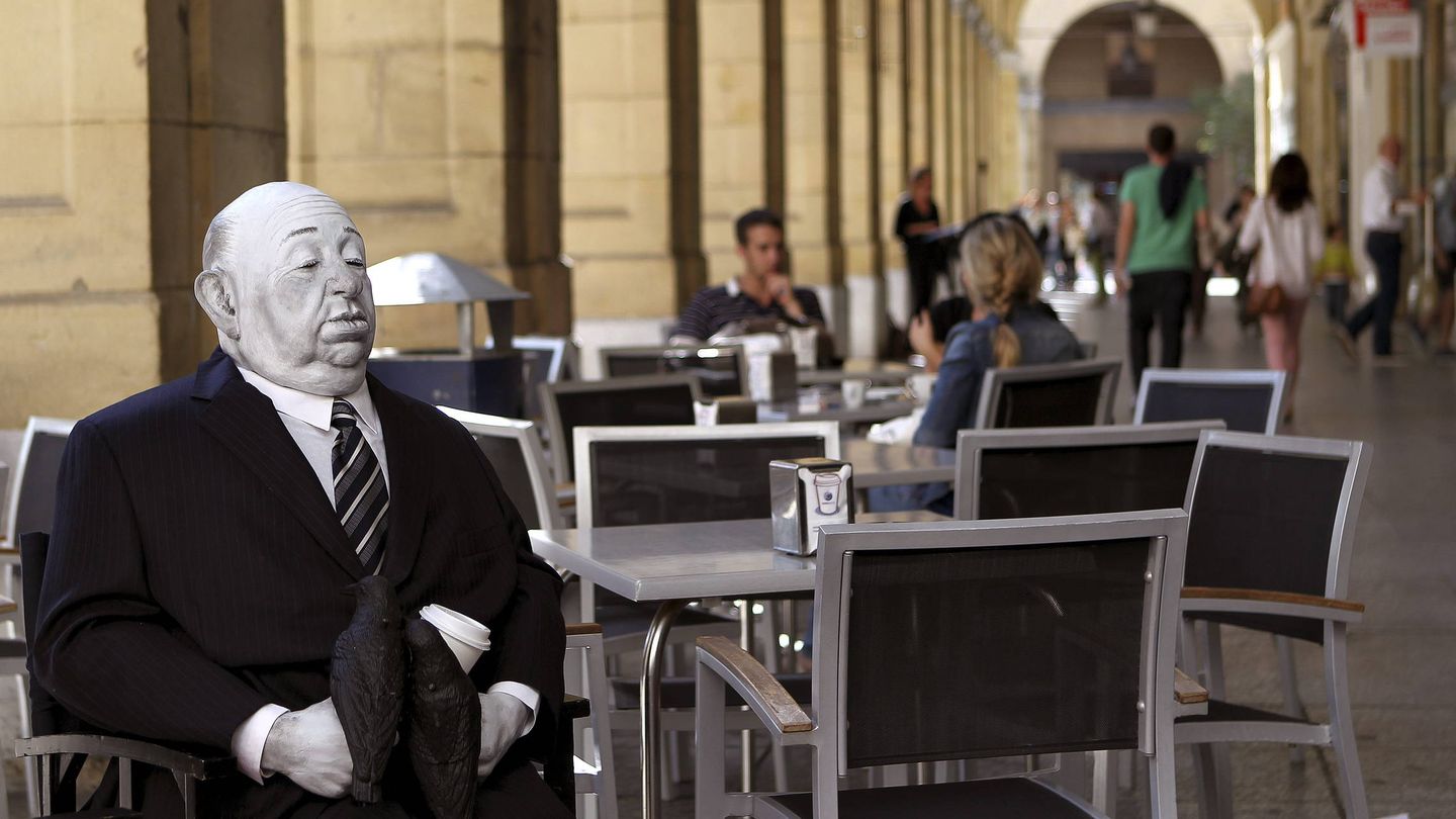 Un Alfred Hitchcock inanimado sorprende a los viandantes en la terraza de una cafetería donostiarra. (EFE/Javier Etxezarreta)