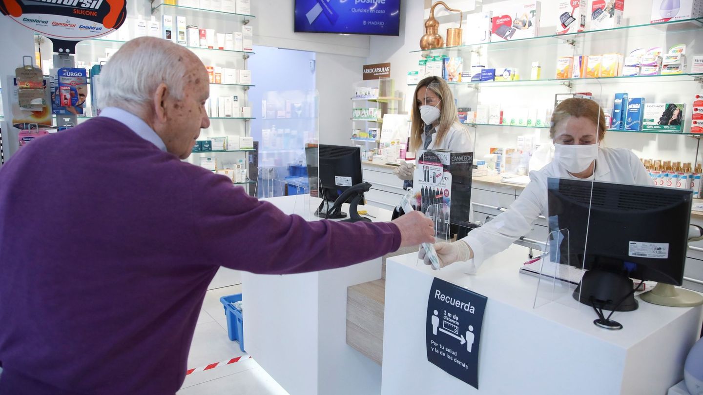 Un cliente mantiene la distancia de seguridad mientras es atendido en una farmacia del centro de Madrid (David Fernández / EFE)