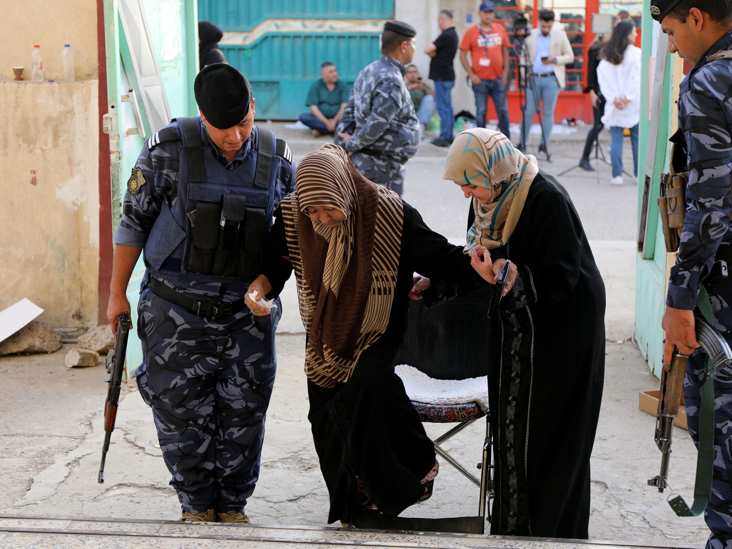 Un policía iraquí ayuda a una mujer a entrar en un centro de votación en Bagdad, el 12 de mayo de 2018. (Reuters)