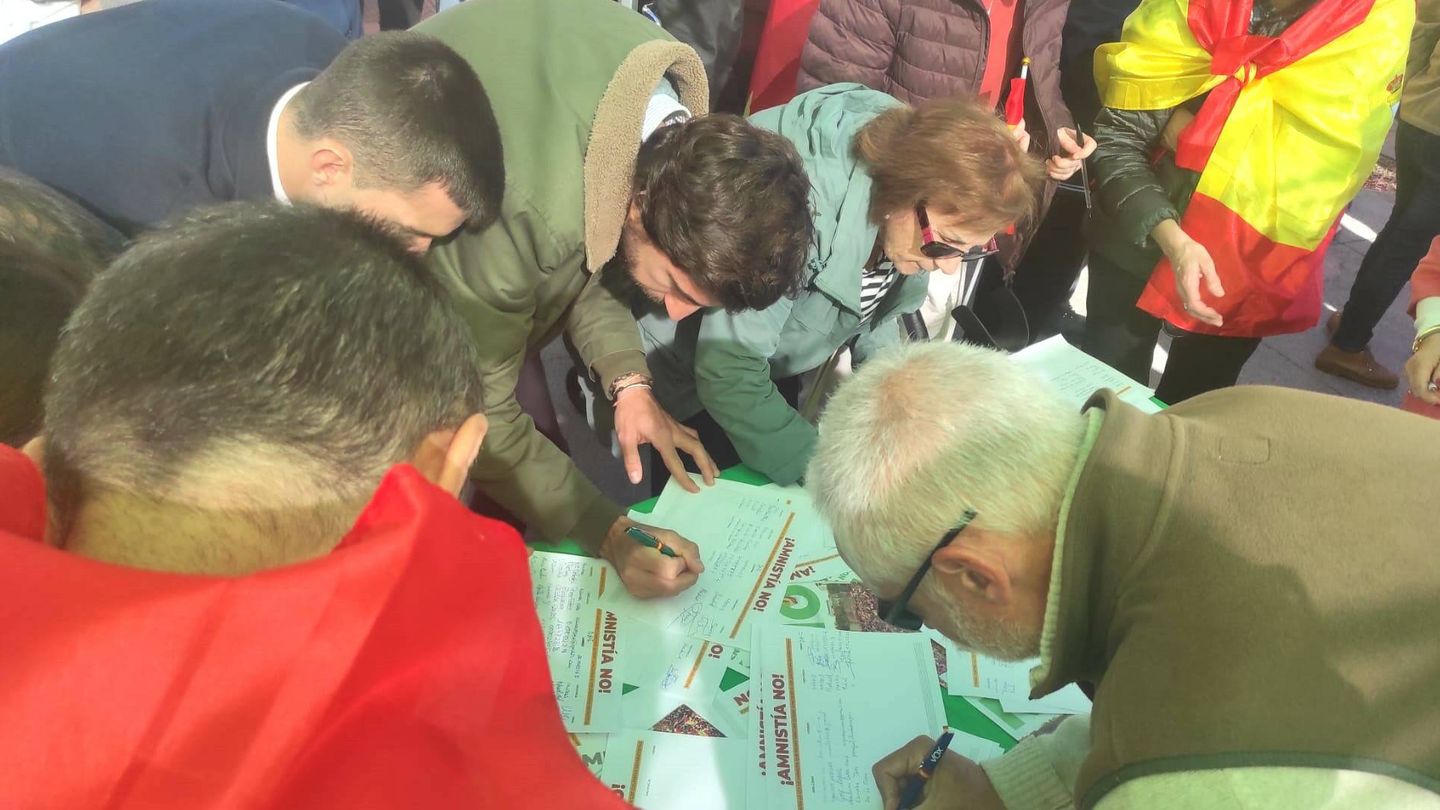 Varias personas firman contra la amnistía en una carpa de Vox, colocada junto a Cibeles. (L.B.)