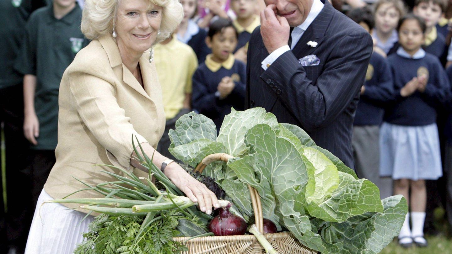 Camilla Parker y el príncipe Carlos de Inglaterra, tras recibir una cesta llena de verduras durante un encuentro con jardineros voluntarios en el parque de St. James. (EFE)