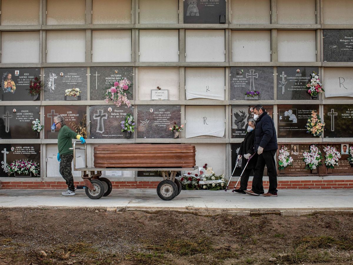 Foto: Un operario de un cementerio de Valencia traslada un féretro seguido por los familiares de la víctima. (EFE)