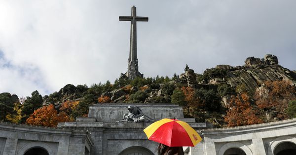 Foto: Una mujer sujeta un paraguas con los colores de la bandera de España en el Valle de los Caídos. (Reuters)