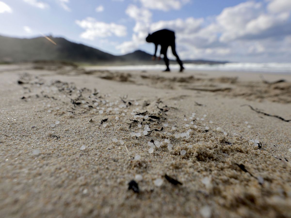 Foto: Una persona recoge 'pellets' en la playa de Traba, en Galicia. (EFE/Cabalar)