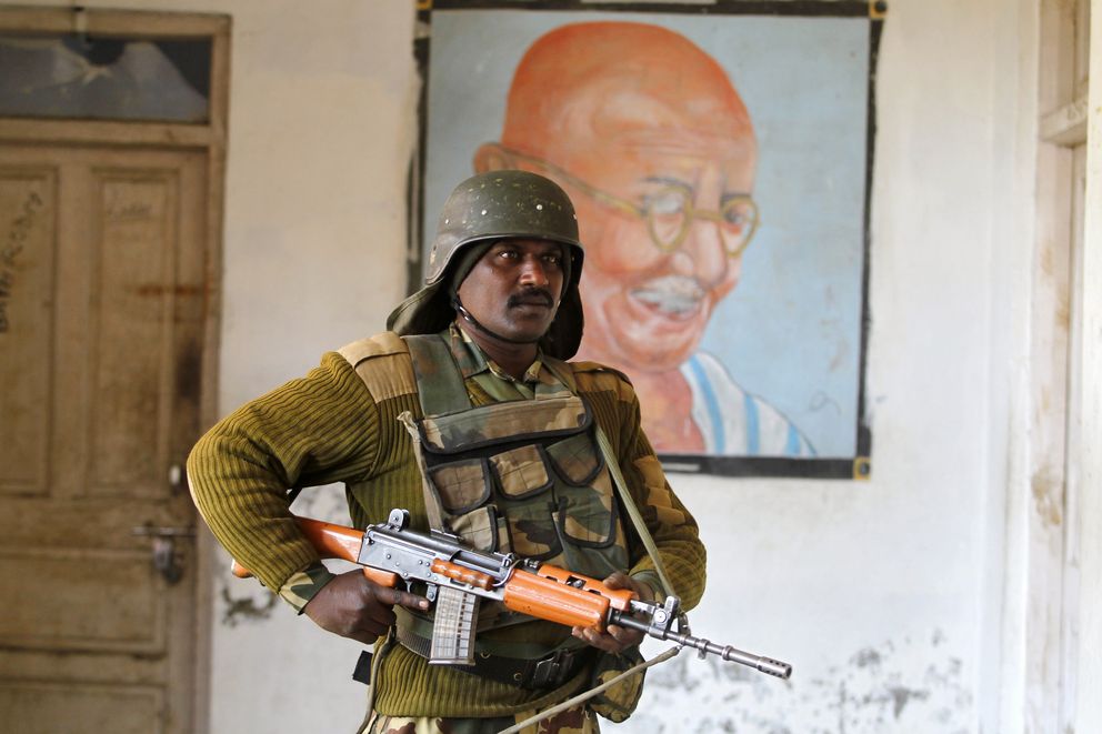 Un militar indio ante un cuadro de Gandhi protege un colegio en Merhama (Reuters).