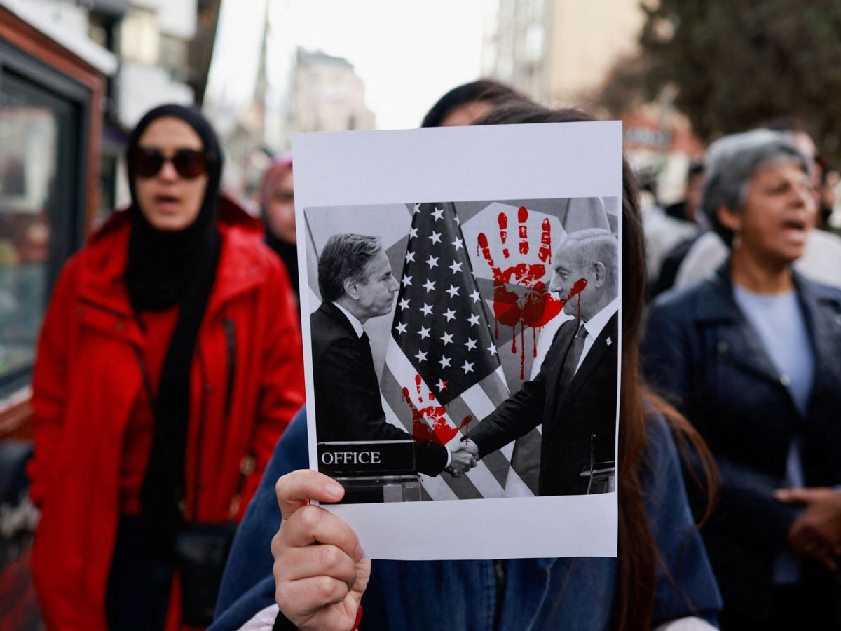 Foto: Una mujer sostiene una imagen en la que aparece el secretario de Estado de EEUU, Antony Blinken, estrechando la mano del primer ministro israelí, Benjamín Netanyahu. (Reuters/Ammar Awad)