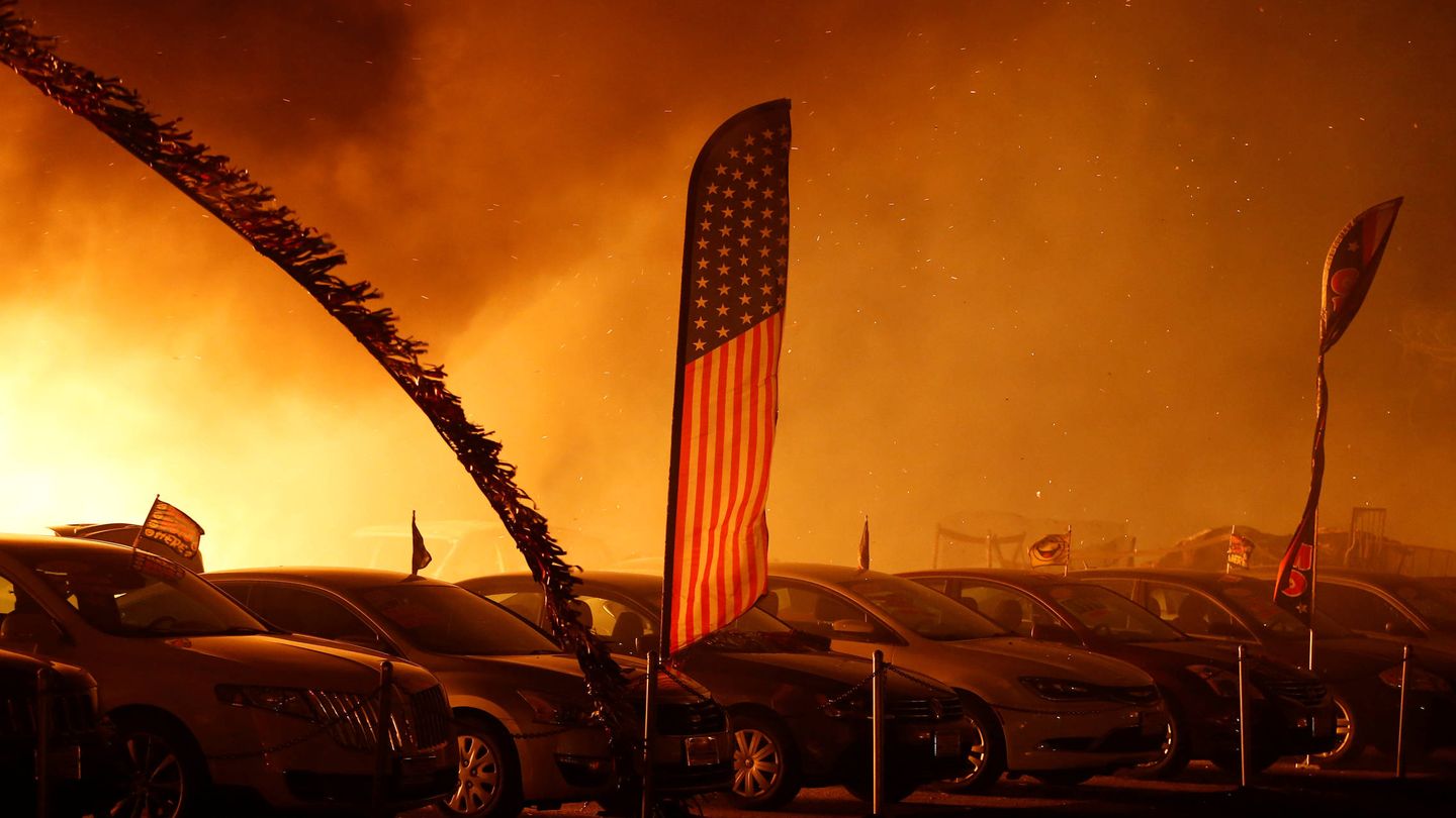 Una bandera estadounidense ondea entre las llamas en un negocio de venta de automóviles en Paradise, California, el 8 de noviembre de 2018. (Reuters)