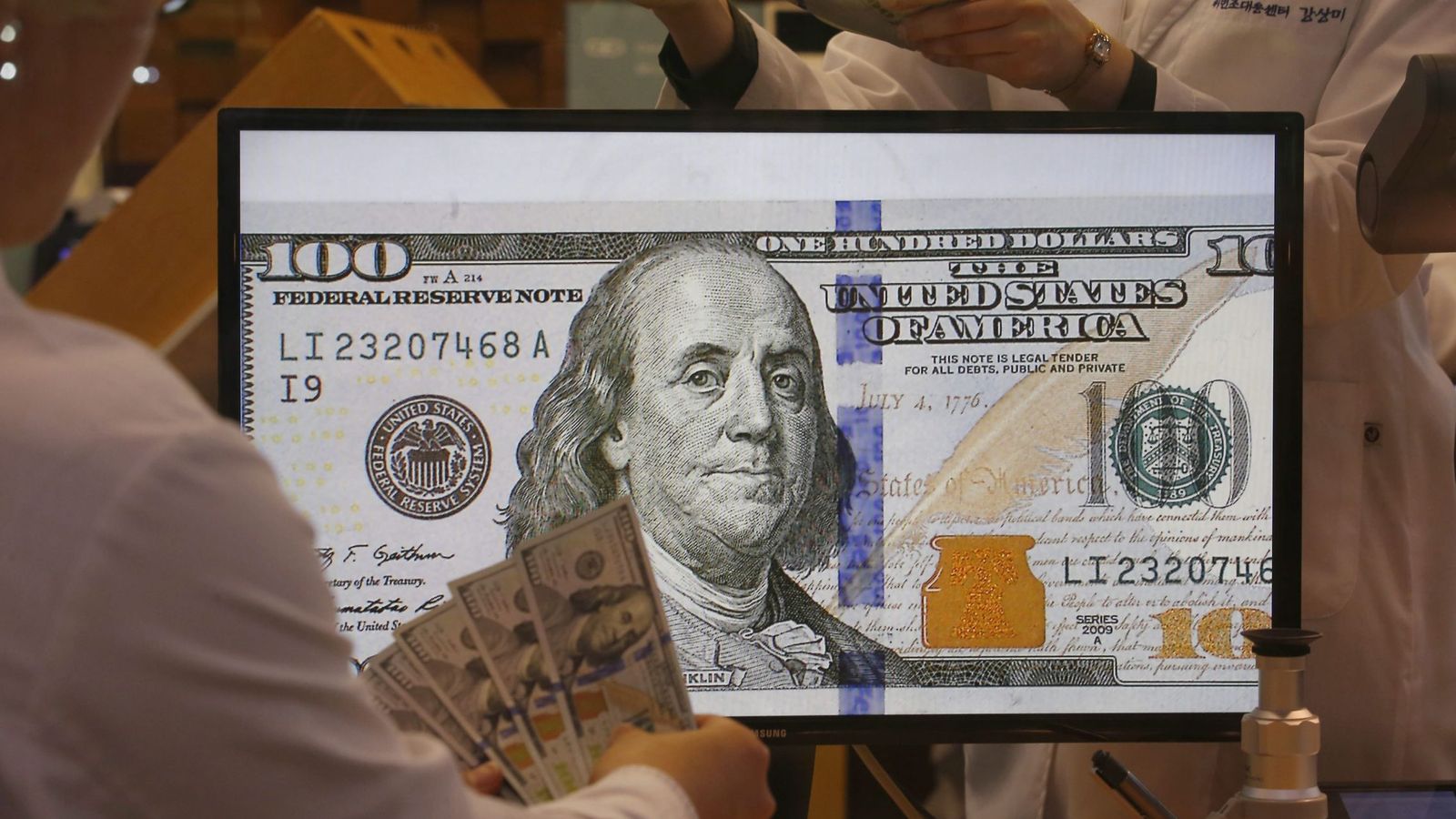 Foto: Un par de trabajsdores revisan billetes de 100 dólares estadounidenses. (EFE)