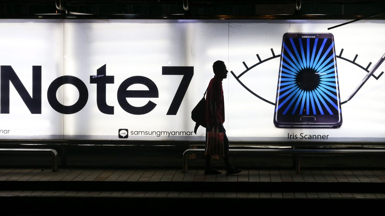 Foto: Un hombra camina junto a una parada de autobús en la que aparece una publicidad del Galaxy Note 7 de Samsung. (Efe)
